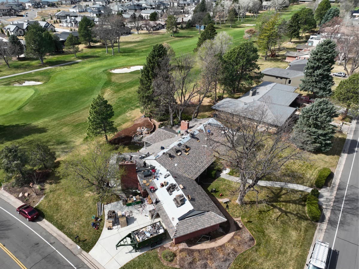Aerial view of large home roof replacement near golf course