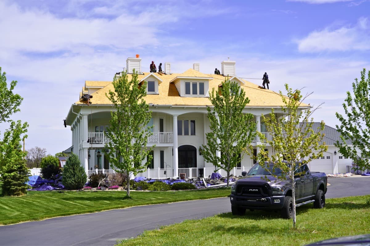 Grand plantation style estate with crew performing full roof tear off